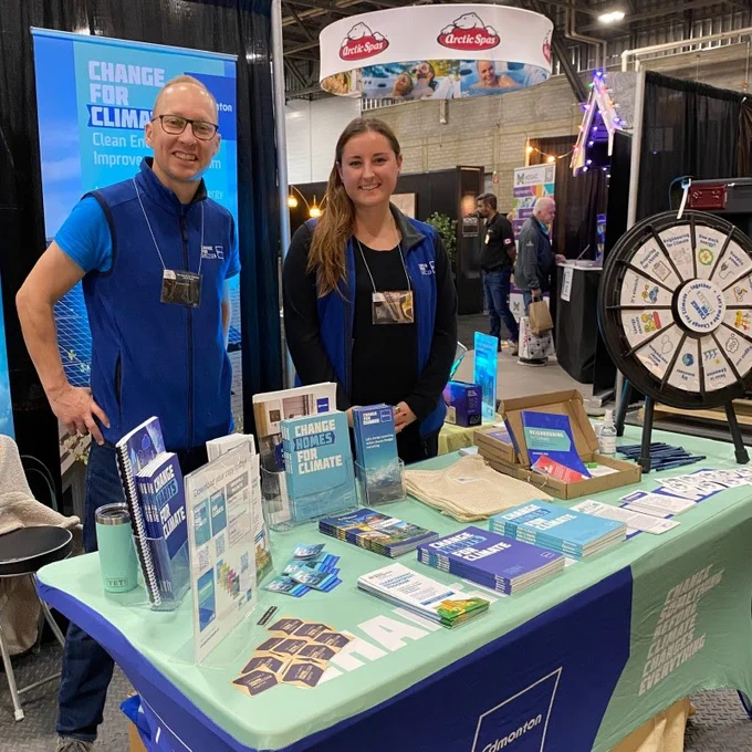 Two members of the Change for Climate team stand behind the table of a booth at the Edmonton Home Renovation show.