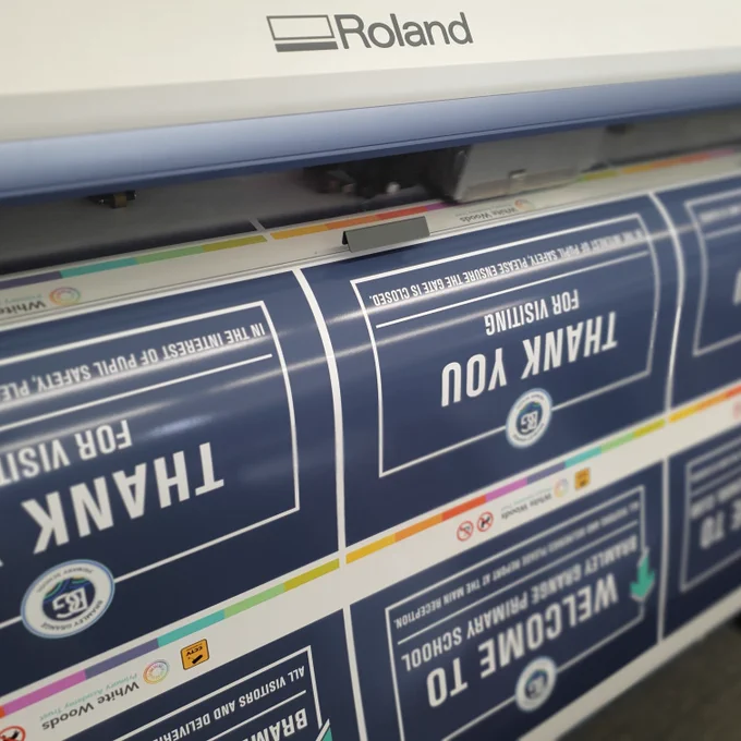 A large format printer producing several graphics for use at a school.  The graphics are grouped evenly across the roll.