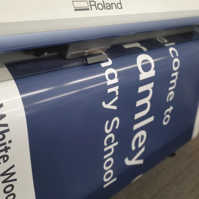 A large format printer producing a graphic for a welcome sign for a school.