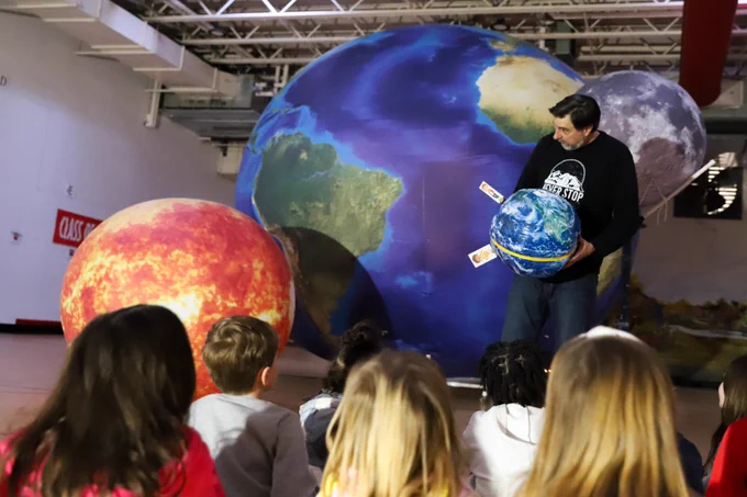 Orbit Earth Expo teacher Pete demonstrates the seasons on earth to a group of first graders