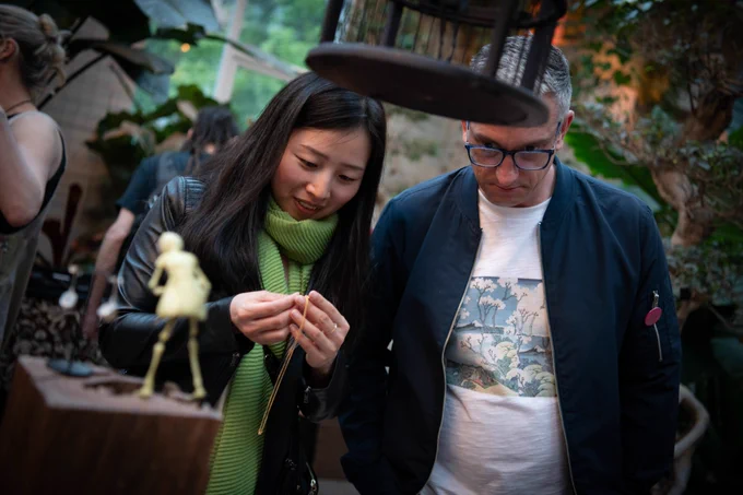 Two people looking at a necklace inside a hall with lots of plants in the background