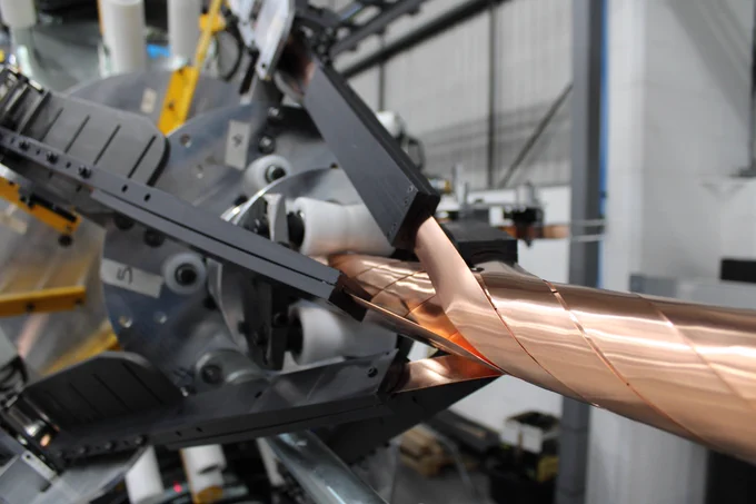 Large machine wrapping a bronze layer of SuperNode's superconducting cable