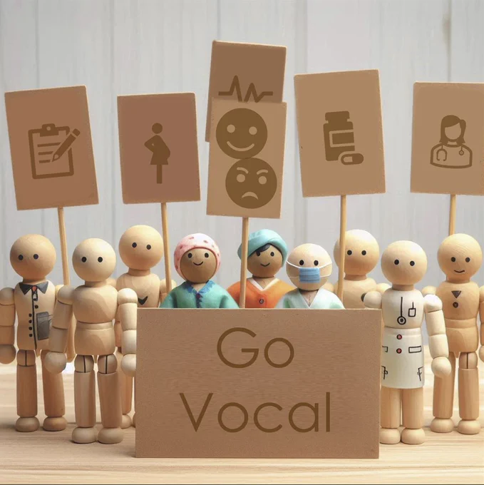 a group of small wooden toy like people, some are dressed in various medical uniforms, they are holding up cardboard signs with icons for health, happy, angry, pregnancy, clipboard etc

In front of them is another cardboard sign that reads the words Go Vocal