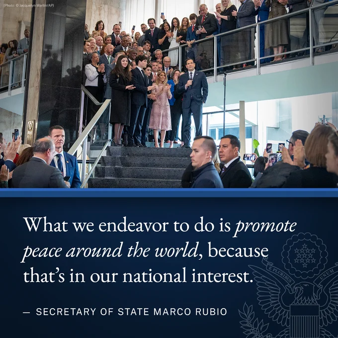 Secretary Rubio stands on the top of a a flight of stairs inside the State Department’s lobby speaking to personnel. Graphic text: What we endeavor to do is promote peace around the world, because that’s in our national interest. - Secretary of State Marco Rubio