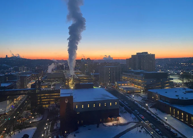 View of the Duquesne University campus at sunrise on a cold and snowy winter day. Steam rises from the campus power plant.