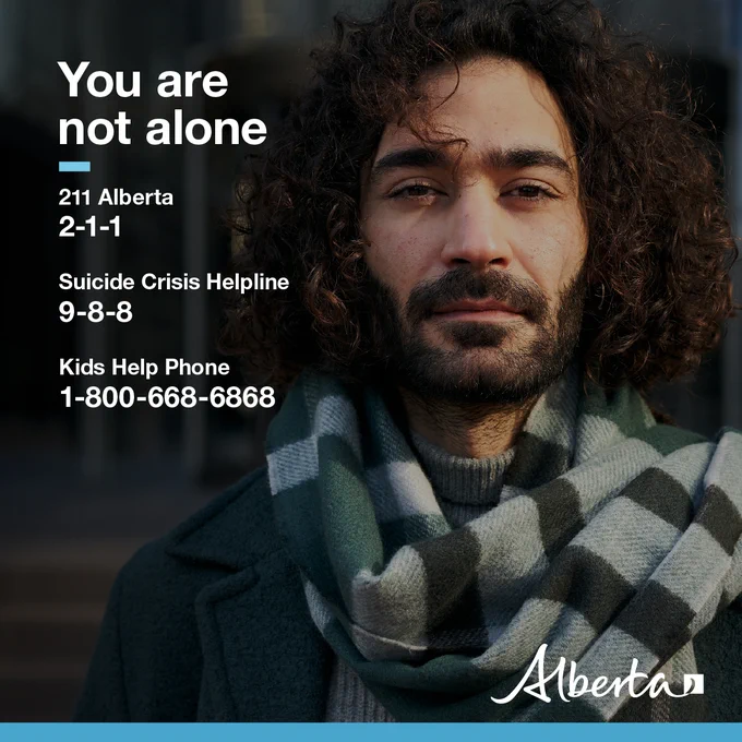 A person looks directly at the camera. Text reads You are not alone. 211 Alberta 2-1-1, Suicide Crisis Helpline 9-8-8, Kids Help Phone 1-800-668-6868. The Alberta government logo is in the bottom right corner.