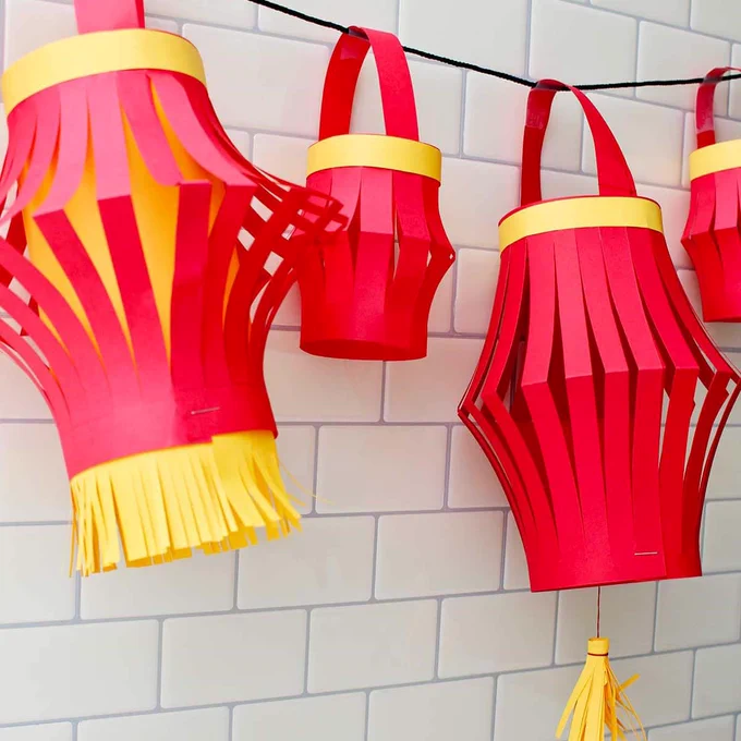 Decorative red paper lanterns hanging against a white tiled wall.