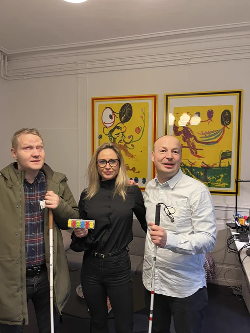 Fra venstre står Jesper Holten, Louise Brown og Ask Abildgaard. Louise Brown står med et navneskilt i hånden, hvor der står Louise med LEGO Braille Bricks.