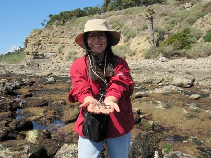 An UNLAB cohort is all smiles holding a wildlife find in the palm of two hands.