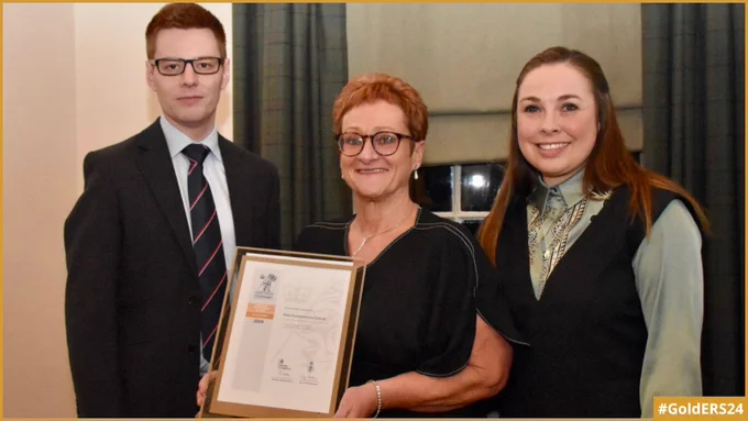The Commanding Officer of HMS Scotia standing next to West Dunbartonshire Council's Strategic People and Change Manager and People and Change Partner, with one of them holding the Gold Award revalidation certificate.