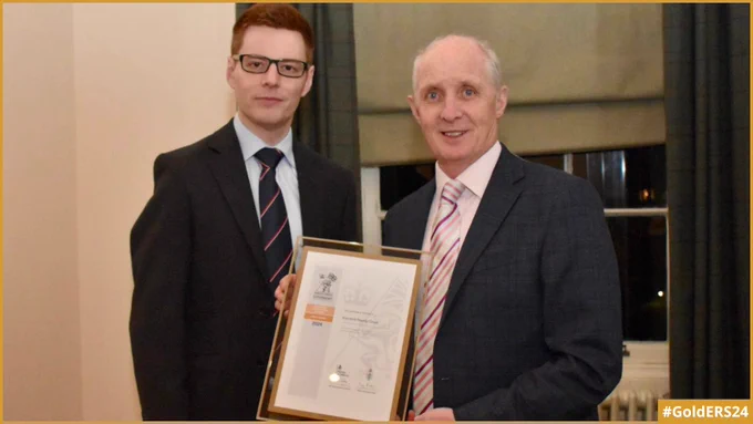 The Commanding Officer of HMS Scotia standing next to the Director of Knockhill Racing Circuit who is holding the Gold Award revalidation certificate.