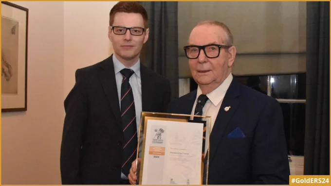The Commanding Officer of HMS Scotia standing next to an Aberdeenshire Councillor holding the Gold Award revalidation certificate.