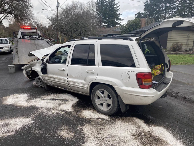 White SUV with heavy damage being loaded onto a flatbed tow truck
