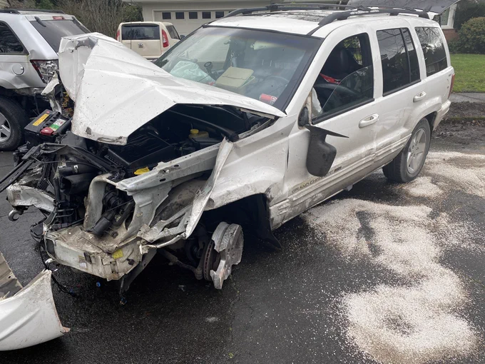 White SUV with heavy front end damage and a front left wheel worn down to the hub
