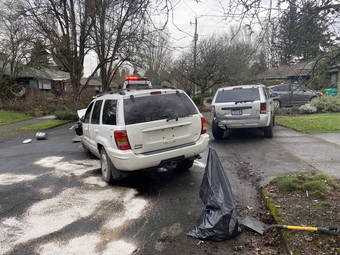 Rear view of a damaged white SUV and the parked silver SUV that was struck