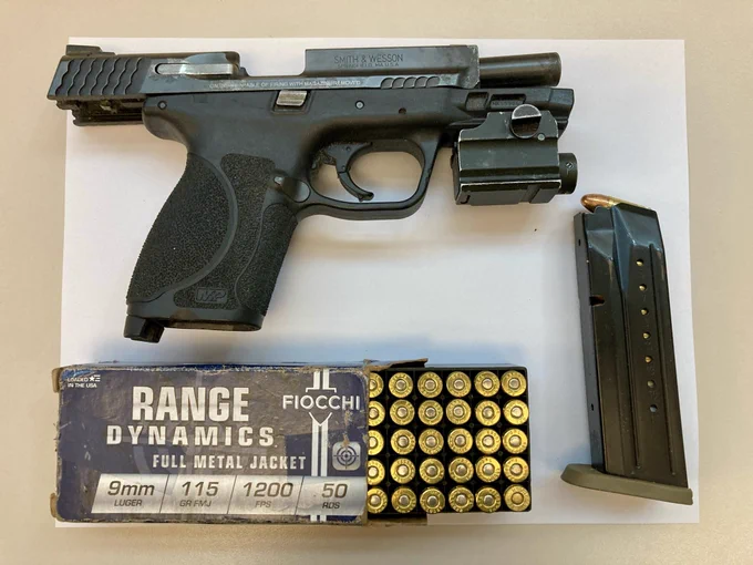 Black semiautomatic handgun with slide locked back next to loaded magazine and box of 9mm ammunition