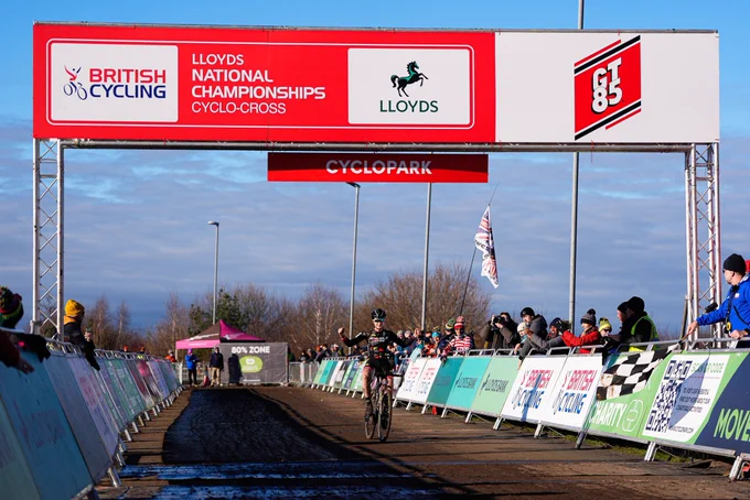 Zoe Roche crossing the line as spectators cheer her on