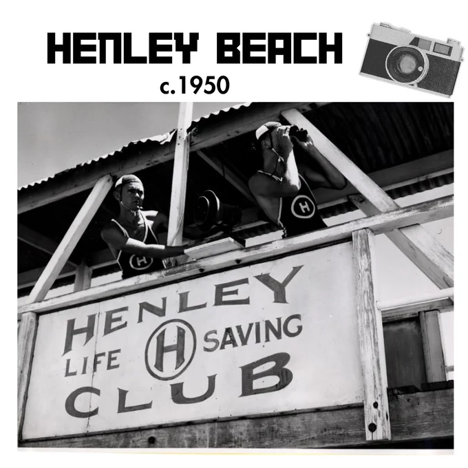 Two life savers keeping a lookout from a beach tower with a sign on it that says 'Henley Life Saving Club'