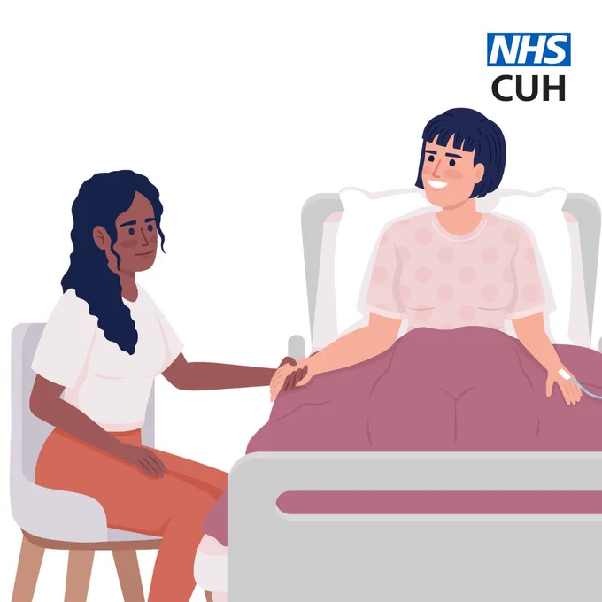 A woman in a chair holding the hand of a woman sitting in a bed 