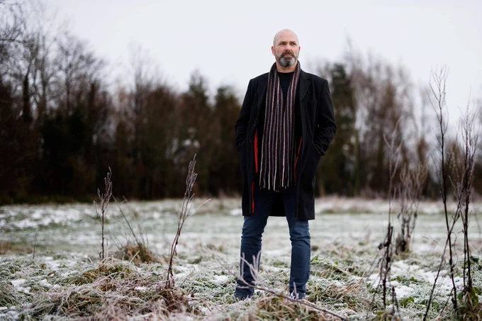A photograph of Irish author Donal Ryan stood outside in a winter coat and scarf on a frosty day