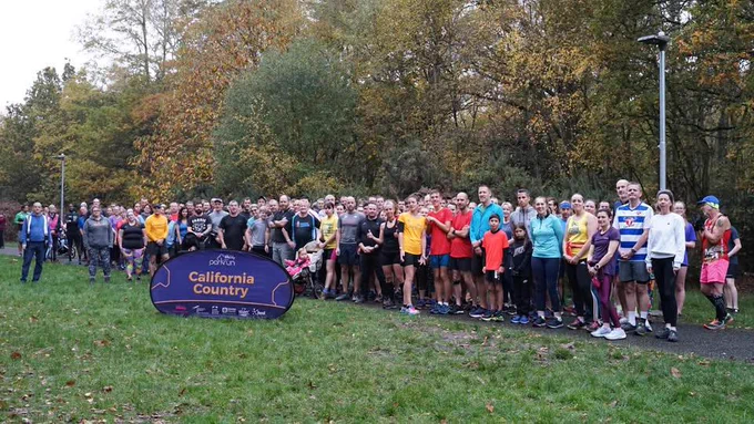 Hundreds of runner crowd round the sign at California Country parkrun