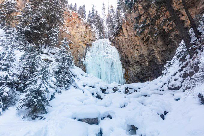 Yellowstone's Lost Creek Falls frozen surrounded by snow. 