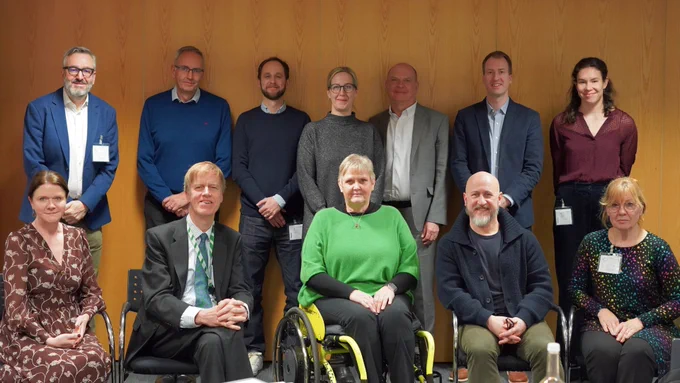 Group photo of the Minister for Social Security and Disability, Sir Stephen Timms MP, seated next to various Disability and Access Ambassadors, including Kate Nicholls OBE and Hector Minto,, with other ambassadors standing behind them, including Tim Hollingsworth OBE and Elizabeth Wooller.