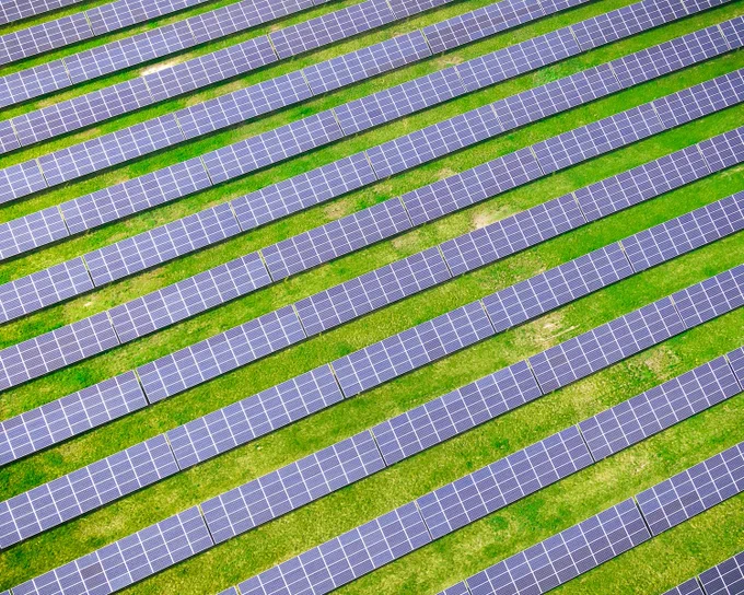 Bird's eye view of rows of solar panels with grass in between.
