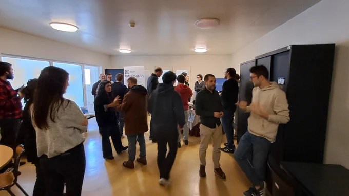 Coffee break room with around 30 people chatting in groups
