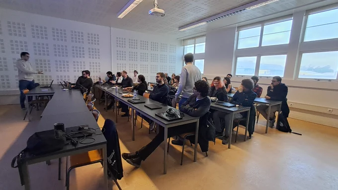 Presentation room with around 35 member listening to a master student presenting his thesis proposal