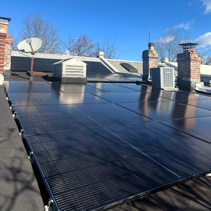 A solar array on a flat roof in DC under a blue sky.