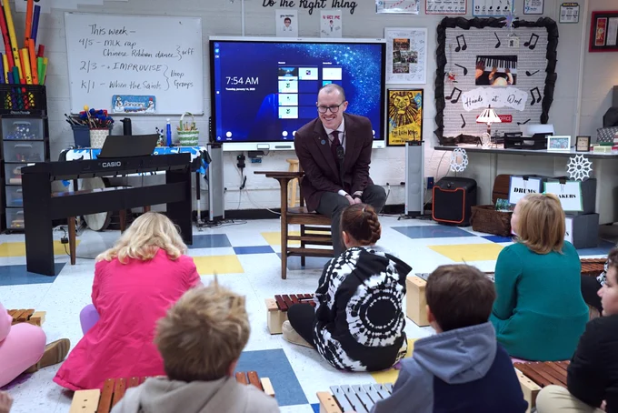 Seth Skiles sitting in a chair in front of a group of students.
