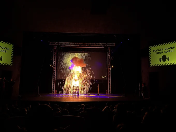 An explosion of sparks and smoke erupts on a theater stage.