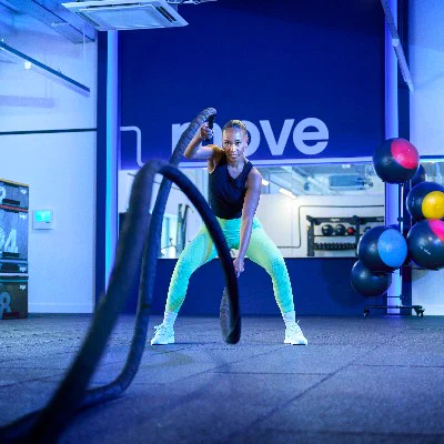 A person exercising with battle ropes in a gym.