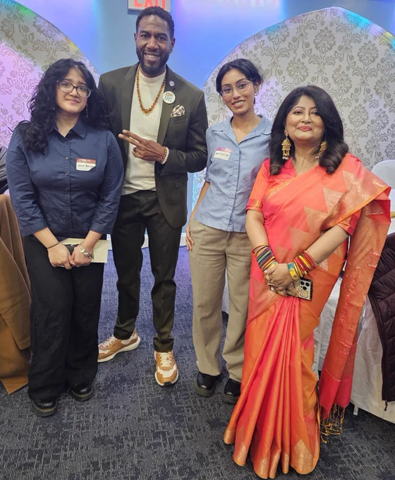 The Public Advocate poses with two young people and a member in a coral and gold sari