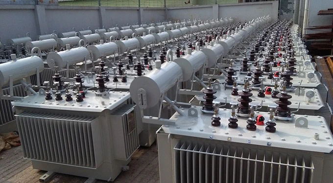 Rows of new industrial transformers at an outdoor storage facility.