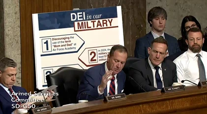A group of Senators sit in front of a chart that incorrectly spells the word "military" as "miltary." 