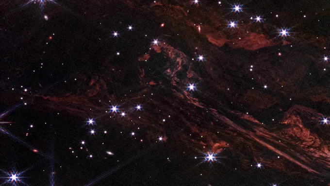 These shimmering cosmic curtains show interstellar gas and dust that has been heated by the flashbulb explosion of a long-ago supernova. The gas then glows infrared light in what is known as a thermal light echo. As the supernova illumination travels through space at the speed of light, the echo appears to expand. NASA’s James Webb Space Telescope observed this light echo in the vicinity of the supernova remnant Cassiopeia A. NASA, ESA, CSA, STScI, J. Jencson (Caltech/IPAC)