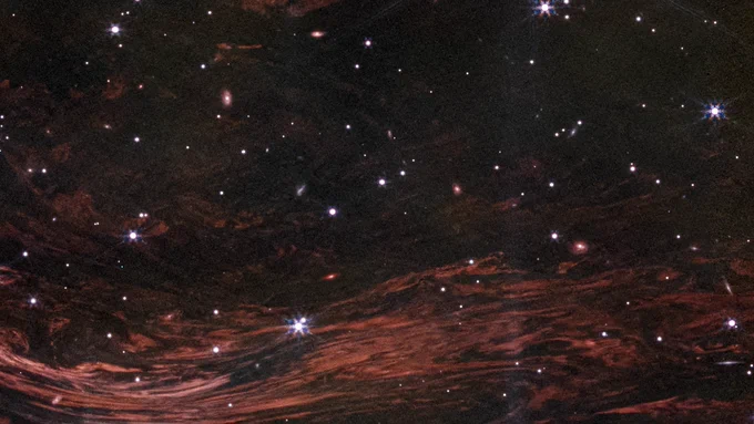 These shimmering cosmic curtains show interstellar gas and dust that has been heated by the flashbulb explosion of a long-ago supernova. The gas then glows infrared light in what is known as a thermal light echo. As the supernova illumination travels through space at the speed of light, the echo appears to expand. NASA’s James Webb Space Telescope observed this light echo in the vicinity of the supernova remnant Cassiopeia A. NASA, ESA, CSA, STScI, J. Jencson (Caltech/IPAC)