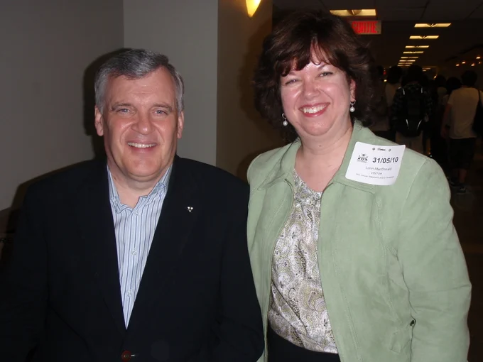 A man and a woman are smiling indoors.