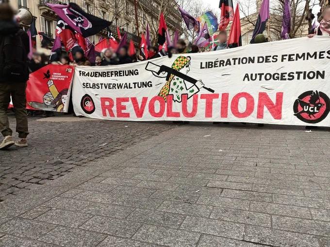 Banderole Die Plattform sous une marée de drapeaux UCL avec tout à gauche un camarade avec un mégaphone