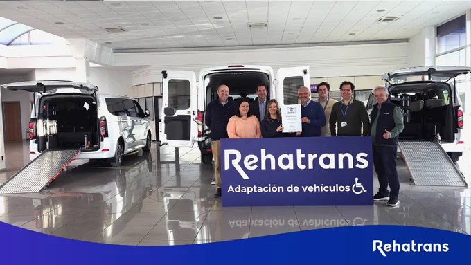 Un grupo de personas con un cartel de Rehatrans en las instalaciones de Rehatrans