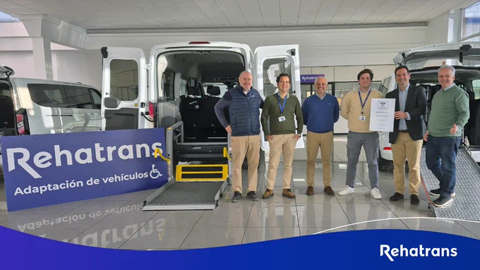 Un grupo de personas con un cartel de Rehatrans en las instalaciones de Rehatrans delante de un vehículo adaptado