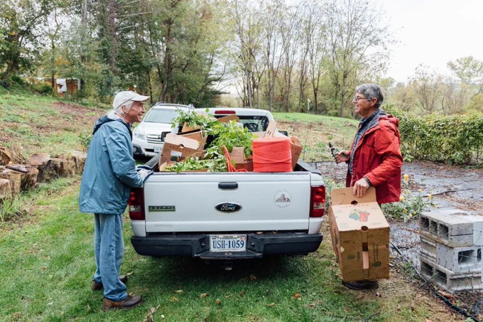 John speaks with a Master Gardener volunteer standing next to a truck bed filled with produce and supplies