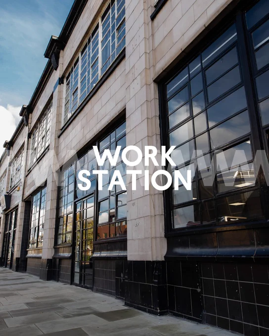 Exterior of the Work Station building with large windows and text overlay reading "WORK STATION" on a clear day.