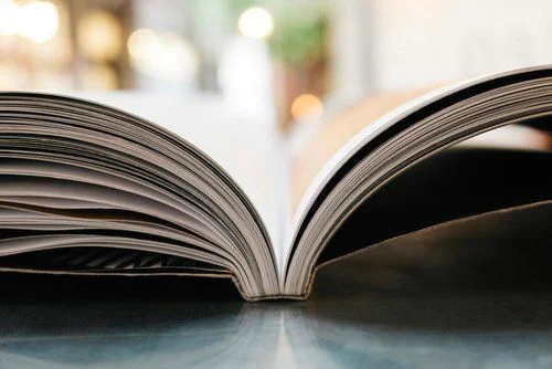 Thick book open to a middle page, background of bright light