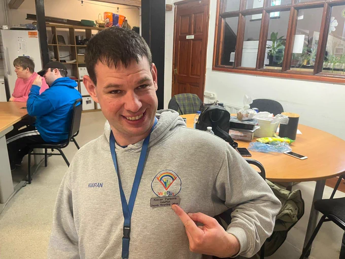 A gentleman pointing to his 'recycling officer' badge