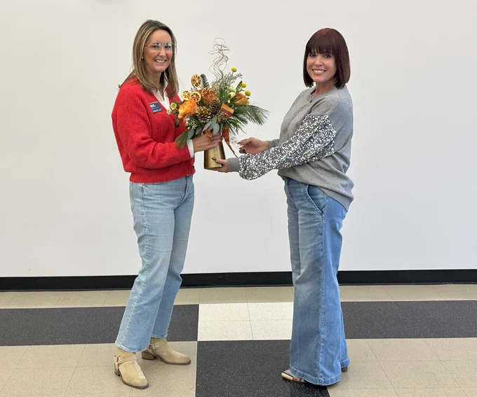Julie Donelon giving a vase of flowers to Leigh Higgins