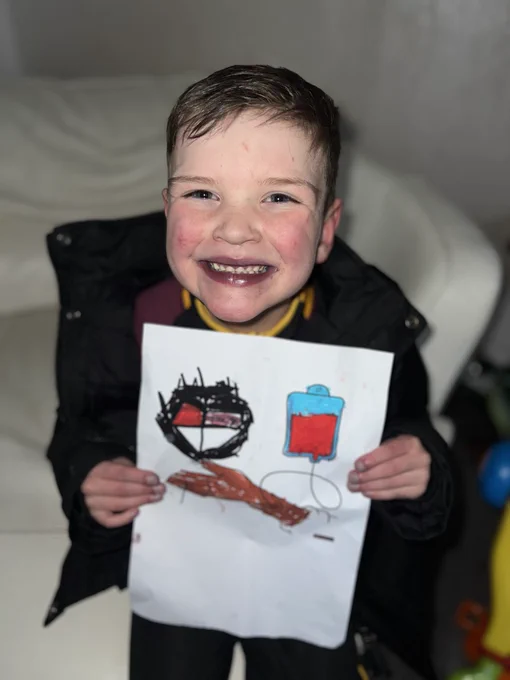 A smiling Dáithí with a drawing he did in school encouraging blood donation.