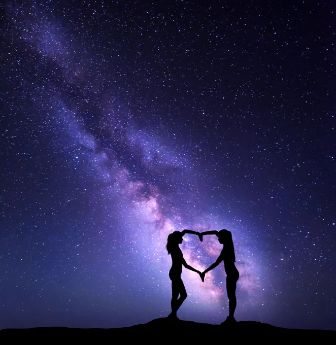 Silhouette of 2 Girls holding hands in a heart shape on the background of the colorful Milky Way. Night landscape with a starry sky. 